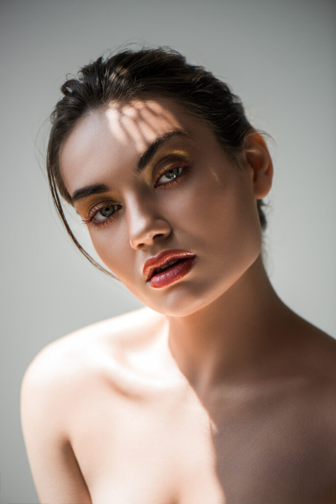 attractive stylish young woman with makeup, isolated on grey